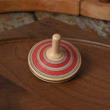 Red Mader Kreiselmanufaktur fado maple wooden finger spinning top placed on a walnut spinning plate in the Babipur playroom.