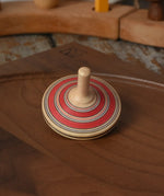 Red Mader Kreiselmanufaktur fado maple wooden finger spinning top placed on a walnut spinning plate in the Babipur playroom.