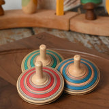 Three Mader Kreiselmanufaktur fado maple wooden finger spinning tops placed on a walnut spinning plate in the Babipur playroom.