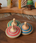 Three Mader Kreiselmanufaktur fado maple wooden finger spinning tops placed on a walnut spinning plate in the Babipur playroom.