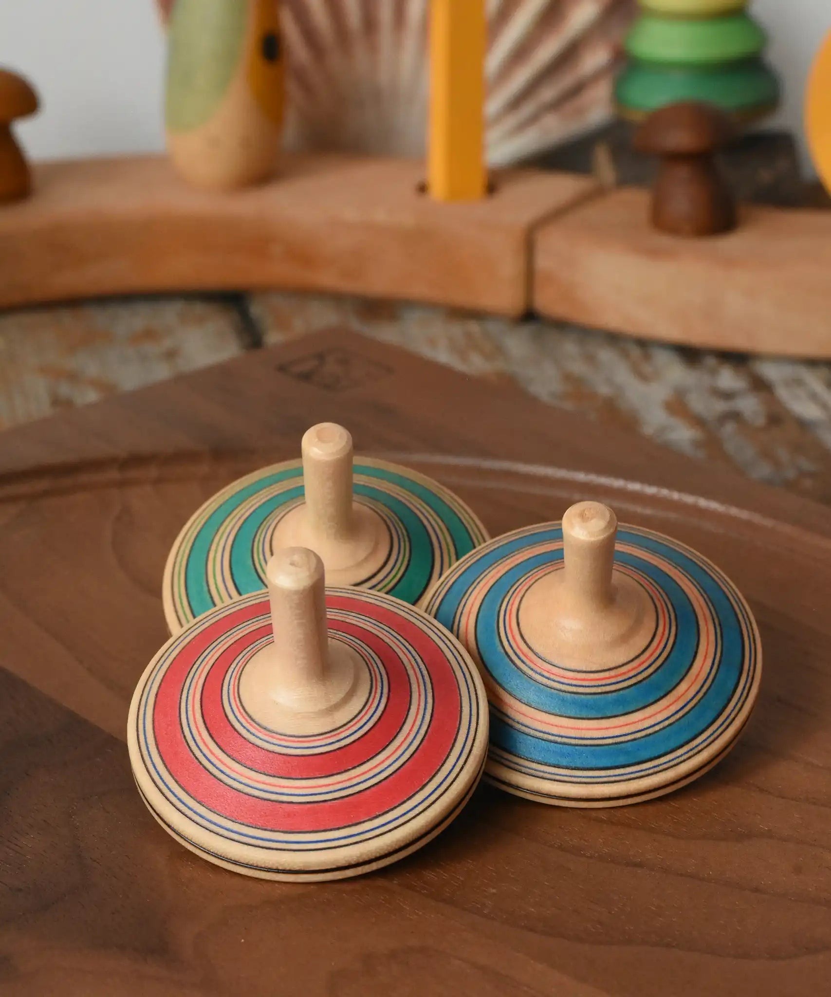 Three Mader Kreiselmanufaktur fado maple wooden finger spinning tops placed on a walnut spinning plate in the Babipur playroom.