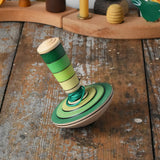 Mader wooden my first spinning top toy with starter in green placed on a wooden surface in the Babipur playroom.