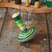 Mader wooden my first spinning top toy with starter in green placed on a wooden surface in the Babipur playroom.