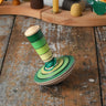 Mader wooden my first spinning top toy with starter in green placed on a wooden surface in the Babipur playroom.