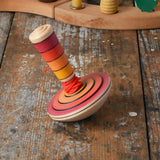 Mader wooden my first spinning top toy with starter in red placed on a wooden surface in the Babipur playroom.