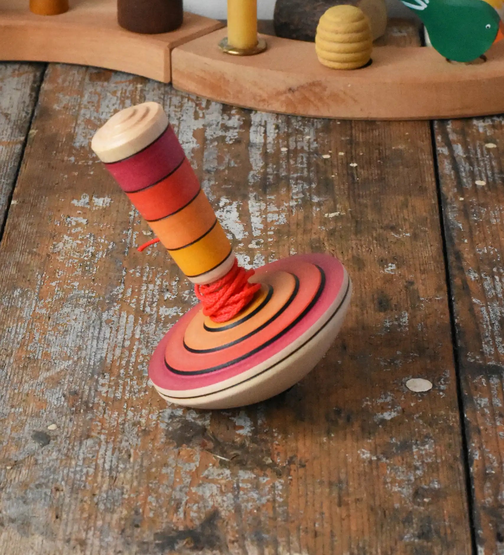 Mader wooden my first spinning top toy with starter in red placed on a wooden surface in the Babipur playroom.