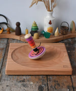 Mader my first spinning top toy with starter in pink placed on a large cherry wood spinning plate in the Babipur playroom. 