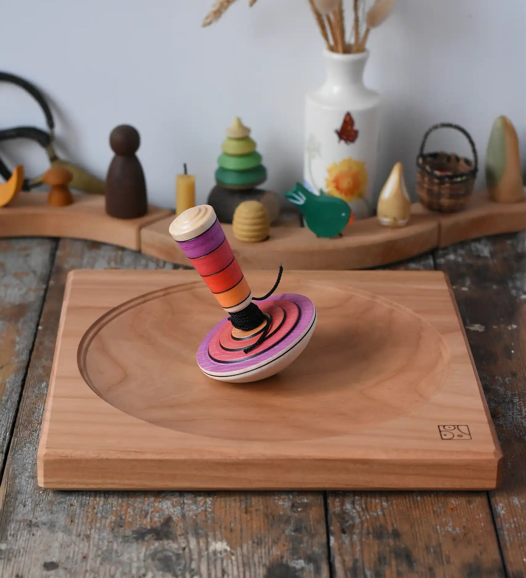 Mader my first spinning top toy with starter in pink placed on a large cherry wood spinning plate in the Babipur playroom. 