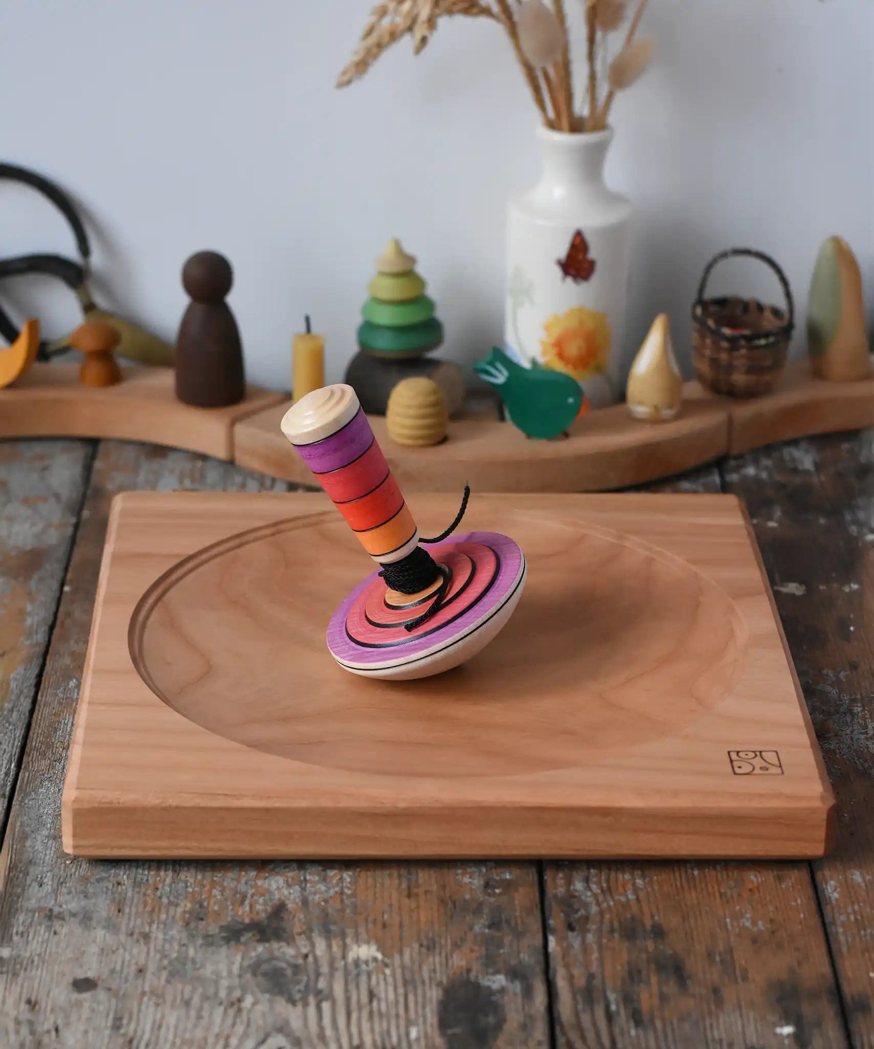 Mader my first spinning top toy with starter in pink placed on a large cherry wood spinning plate in the Babipur playroom. 