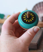 Mader flower egg spinning top in an adult's hand.