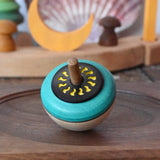 Mader flower egg spinning top placed on a medium walnut spinning plate in the Babipur playroom.