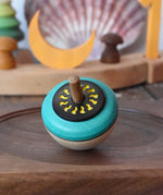 Mader flower egg spinning top placed on a medium walnut spinning plate in the Babipur playroom.