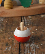 Mader Kreiselmanufaktur fly agaric mushroom turn over spinning top placed on a wooden desk in the Babipur playroom.