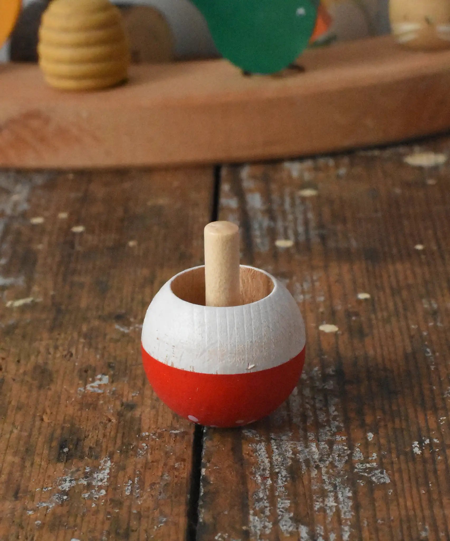 Mader Kreiselmanufaktur fly agaric mushroom turn over spinning top placed on a wooden desk in the Babipur playroom.