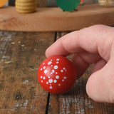 Top of the Mader Kreiselmanufaktur fly agaric mushroom turn over spinning top placed on a wooden desk in the Babipur playroom.