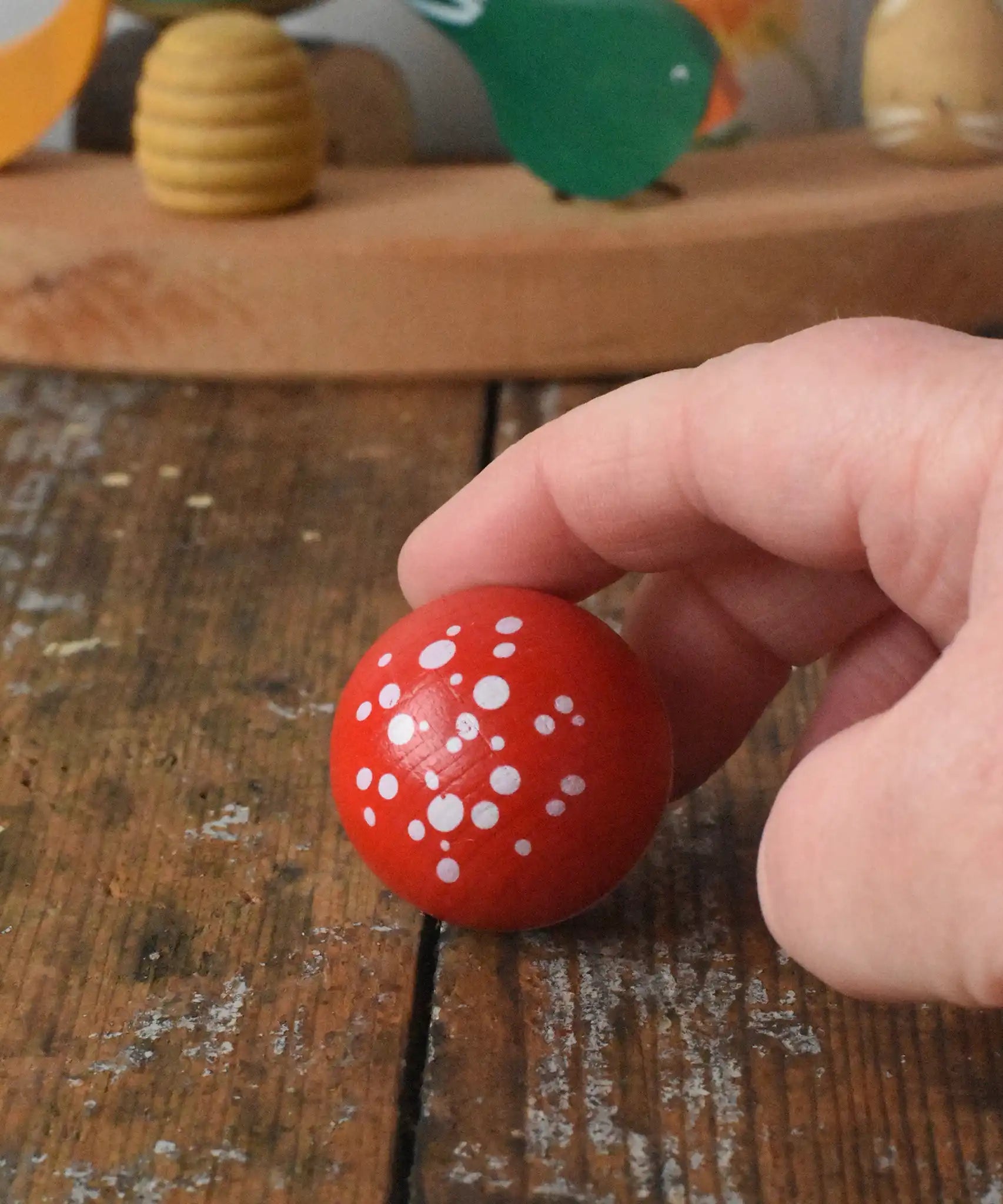 Top of the Mader Kreiselmanufaktur fly agaric mushroom turn over spinning top placed on a wooden desk in the Babipur playroom.