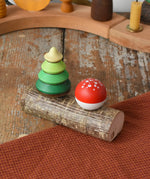 Mader Kreiselmanufaktur forest spinning top set. Green tree spinner and fly agaric mushrrom turn over top that sit on branch with two slots.