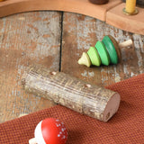 Mader Kreiselmanufaktur forest spinning top set. Green tree spinner and fly agaric mushrrom turn over top that with a branch with two slots. The spinners have been taken out and placed on the wooden desk.