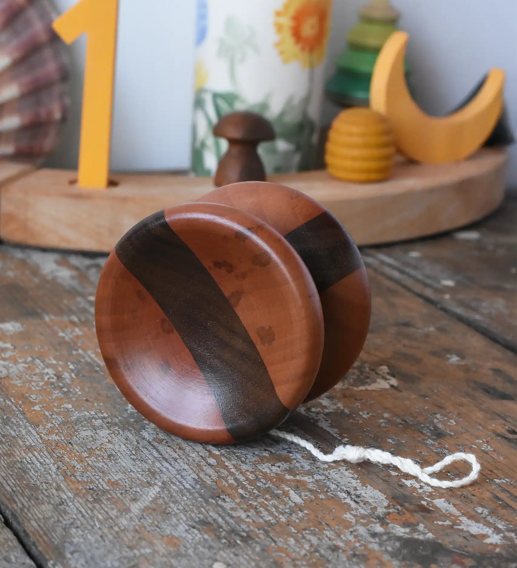 Mader free wheel butterfly yoyo placed on a wooden surface in the Babipur playroom. Walnut and pear wood toy. 