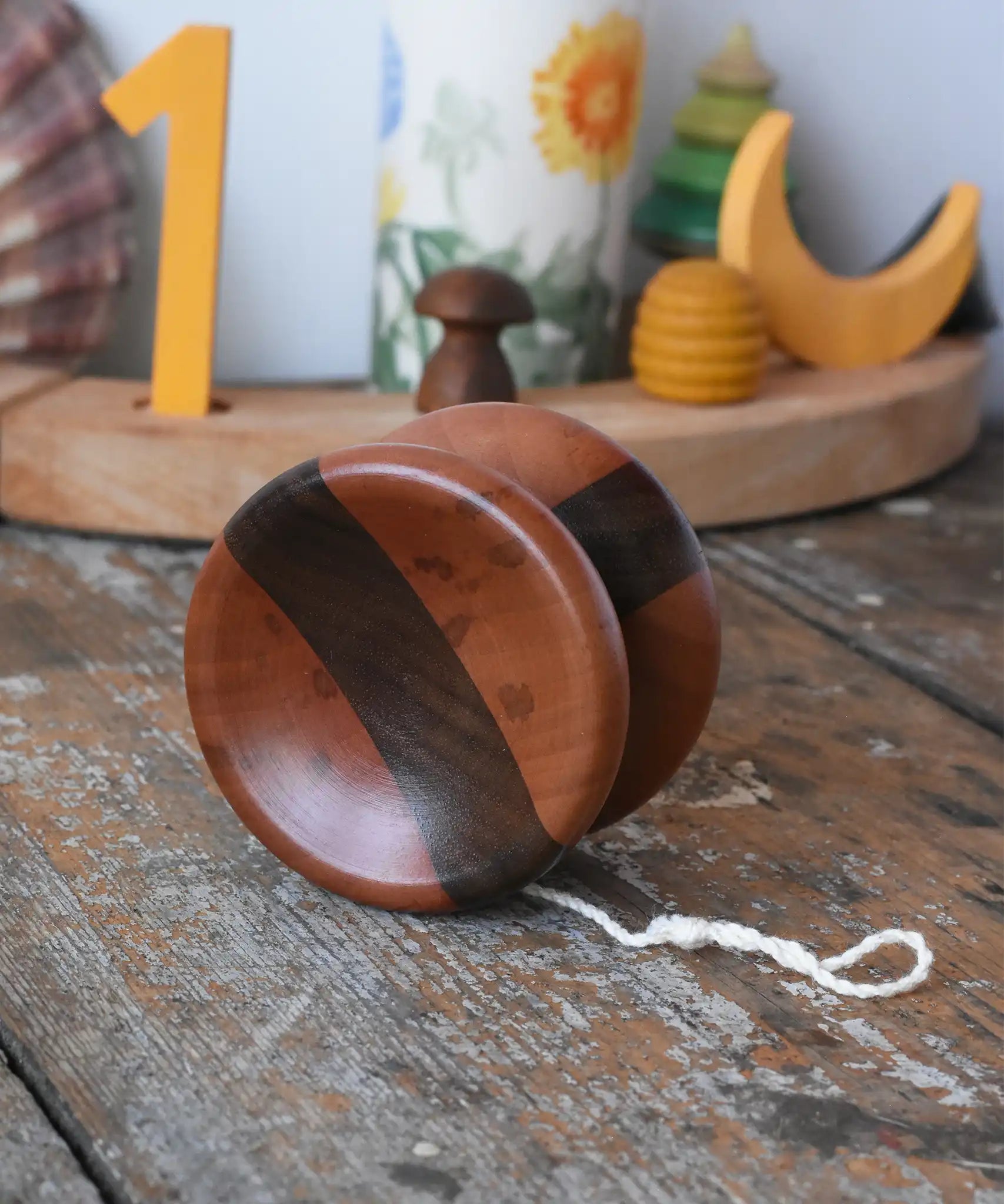 Mader free wheel butterfly yoyo placed on a wooden surface in the Babipur playroom. Walnut and pear wood toy. 