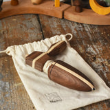 Mader goliath thunderbolt wooden spinning top with starter in a dark wood placed on a cotton drawstring storage bag in the Babipur playroom.