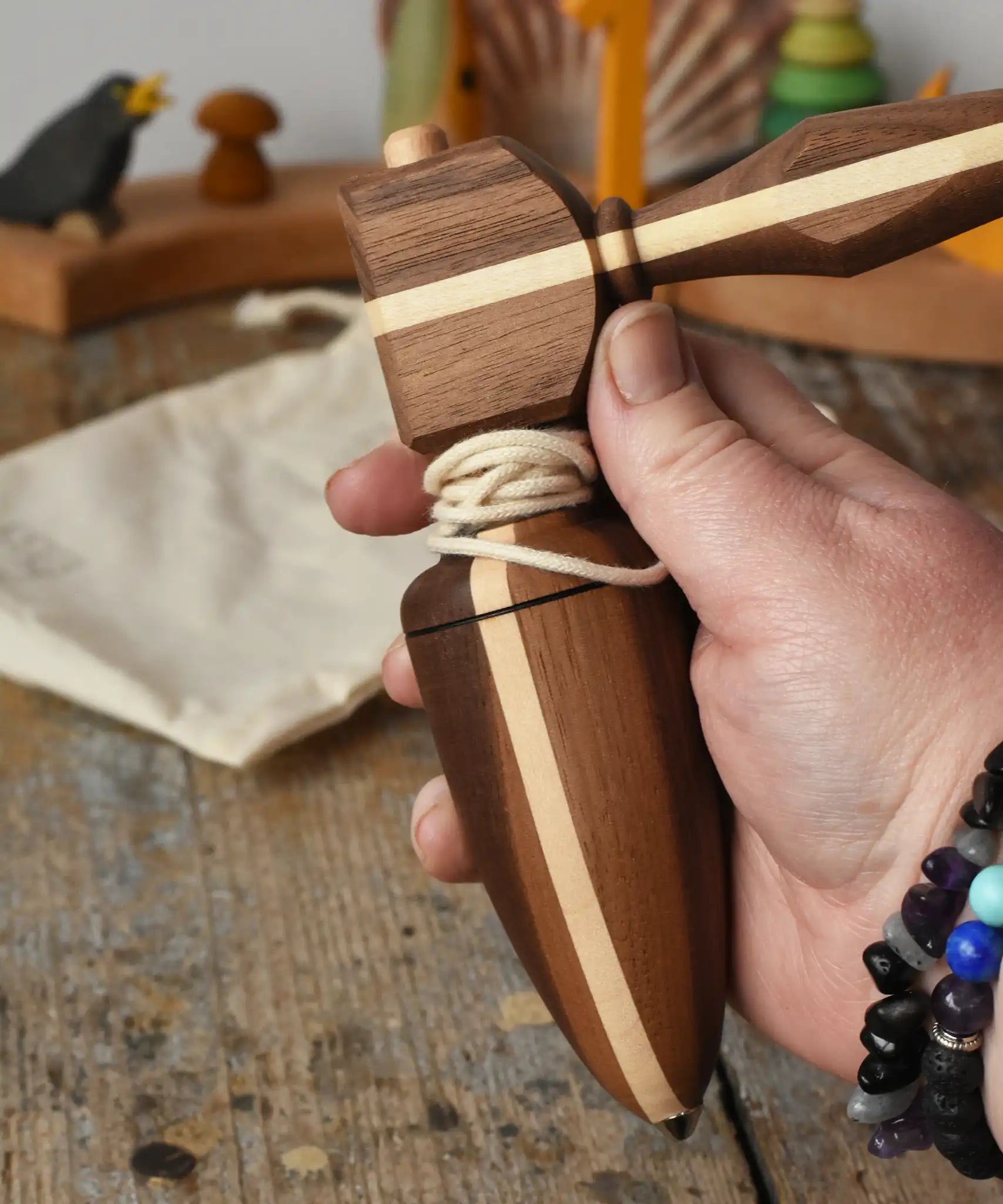 Mader goliath thunderbolt wooden spinning top with starter in an adult's hand in the Babipur playroom.