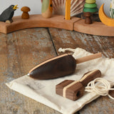 Mader goliath thunderbolt wooden spinning top with starter in a dark wood placed on a cotton storage bag in the Babipur playroom.