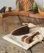 Mader goliath thunderbolt wooden spinning top with starter in a dark wood placed on a cotton storage bag in the Babipur playroom.