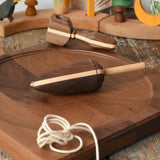 Mader goliath thunderbolt wooden spinning top with starter in a dark wood placed on a walnut wood spinning plate in the Babipur playroom.
