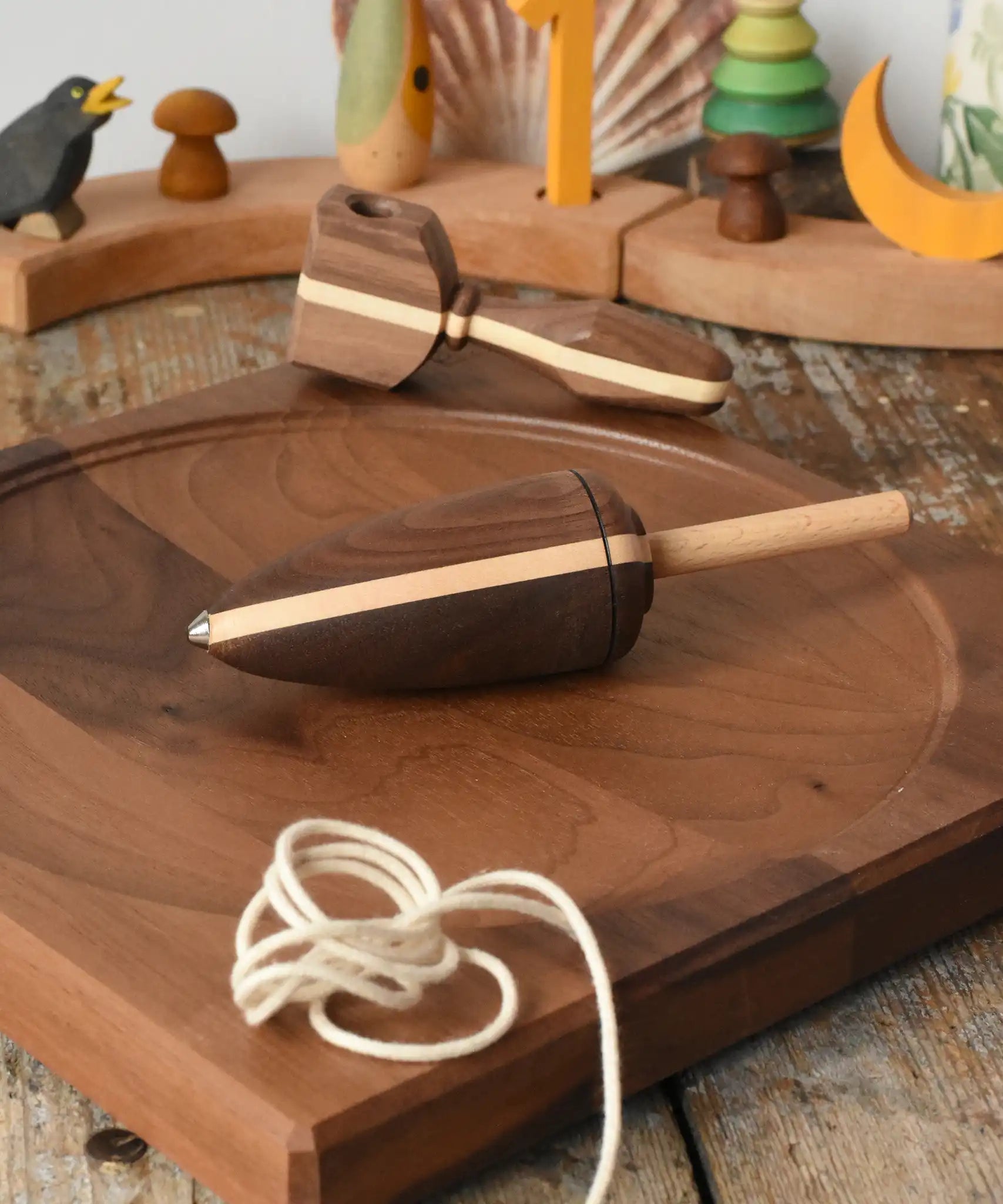 Mader goliath thunderbolt wooden spinning top with starter in a dark wood placed on a walnut wood spinning plate in the Babipur playroom.