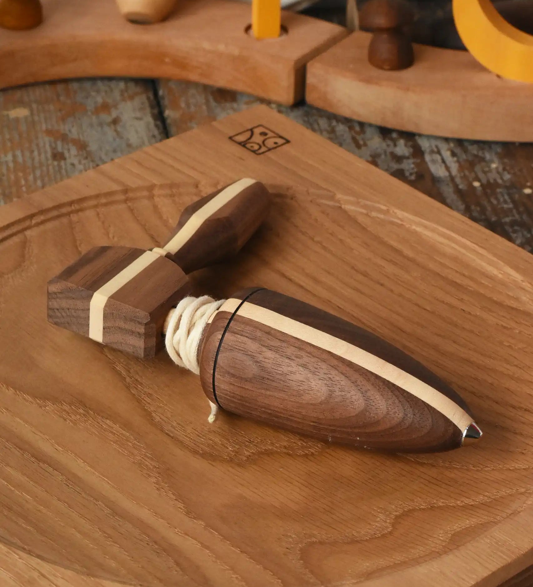 Mader goliath thunderbolt wooden spinning top with starter in a dark wood placed on an oak spinning plate in the Babipur playroom.