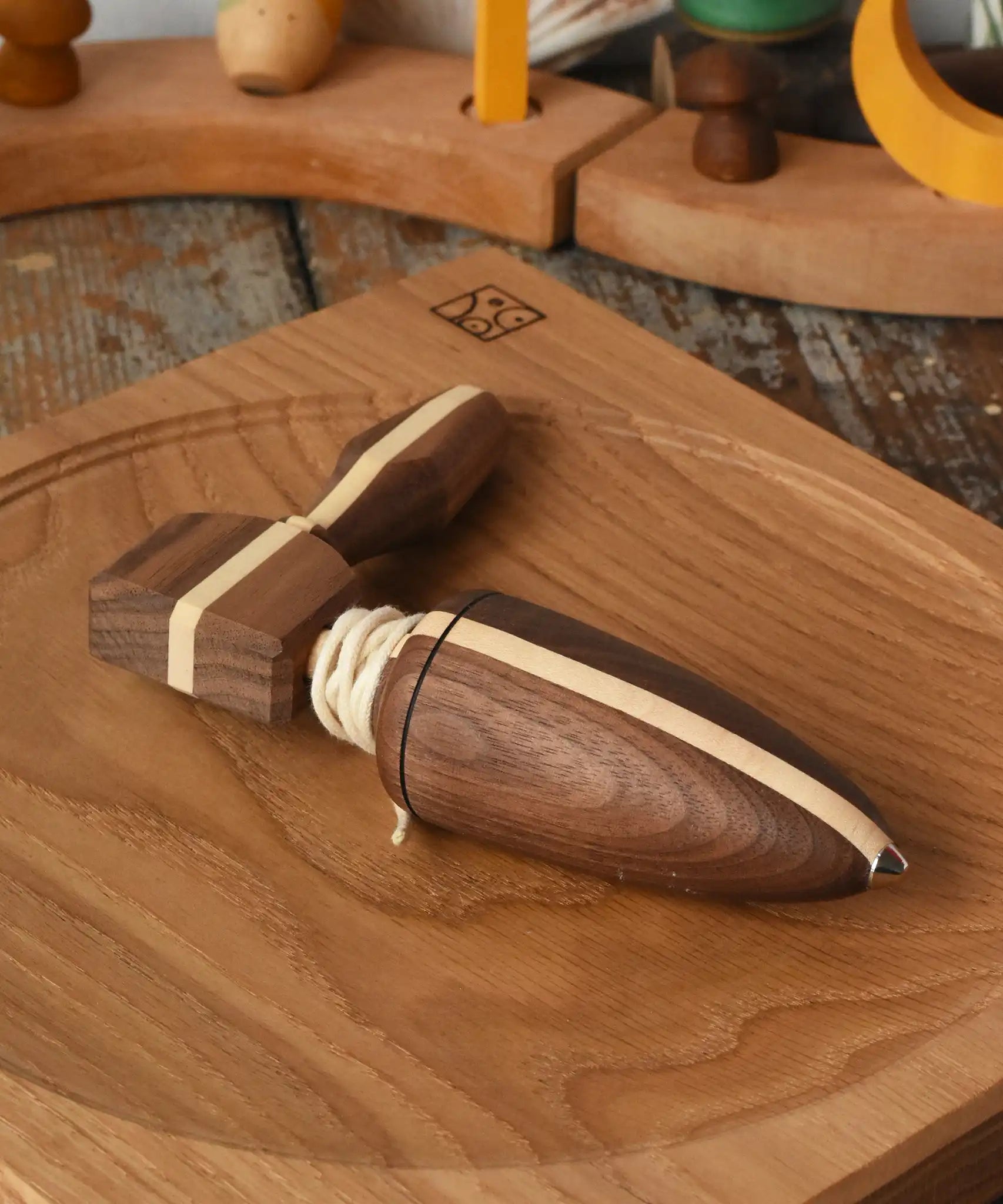 Mader goliath thunderbolt wooden spinning top with starter in a dark wood placed on an oak spinning plate in the Babipur playroom.