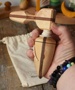 Mader goliath thunderbolt wooden spinning top with starter in an adult's hand in the Babipur playroom.