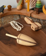 Mader goliath thunderbolt wooden spinning top with starter placed on a walnut spinning plate in the Babipur playroom.
