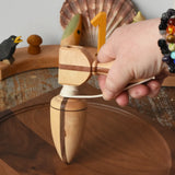 Mader goliath thunderbolt wooden spinning top with starter placed on a walnut spinning plate in the Babipur playroom. It is held upright by and adult's hand.