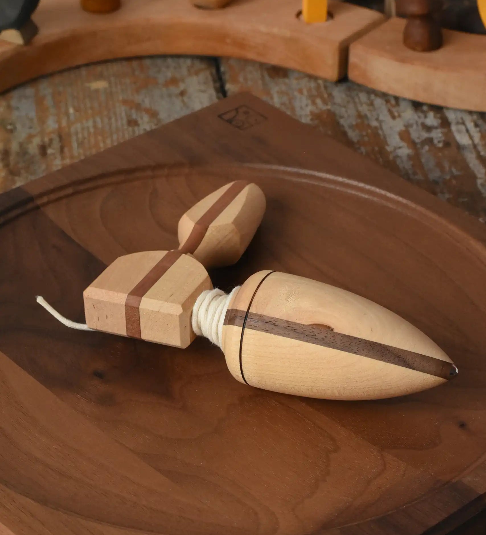 Mader goliath thunderbolt wooden spinning top with starter placed on a walnut spinning plate in the Babipur playroom.