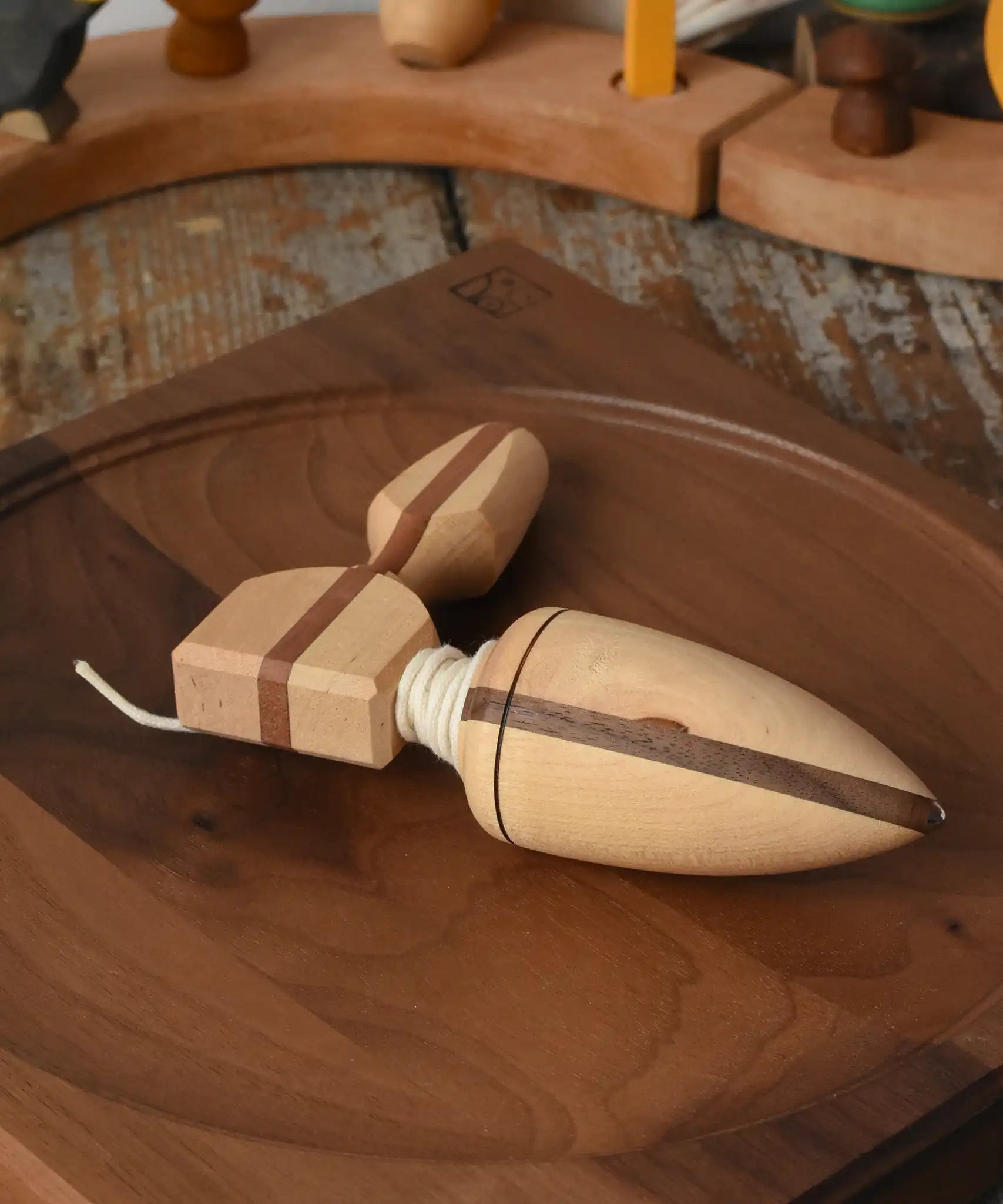 Mader goliath thunderbolt wooden spinning top with starter placed on a walnut spinning plate in the Babipur playroom.