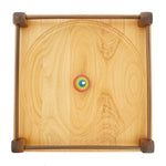 Top view of a rainbow spinning top on the Mader 40cm large Manege Spinning Plate on a white background