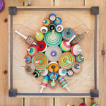 Mader handmade Manege wooden spinning plate on a wooden floor covered in various Mader spinning top toys