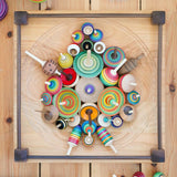 Mader handmade Manege wooden spinning plate on a wooden floor covered in various Mader spinning top toys