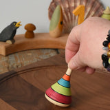 Mader harlekin spinning top being placed on a walnit spinning plate in the Babipur playroom.