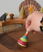 Mader harlekin spinning top being placed on a walnit spinning plate in the Babipur playroom.