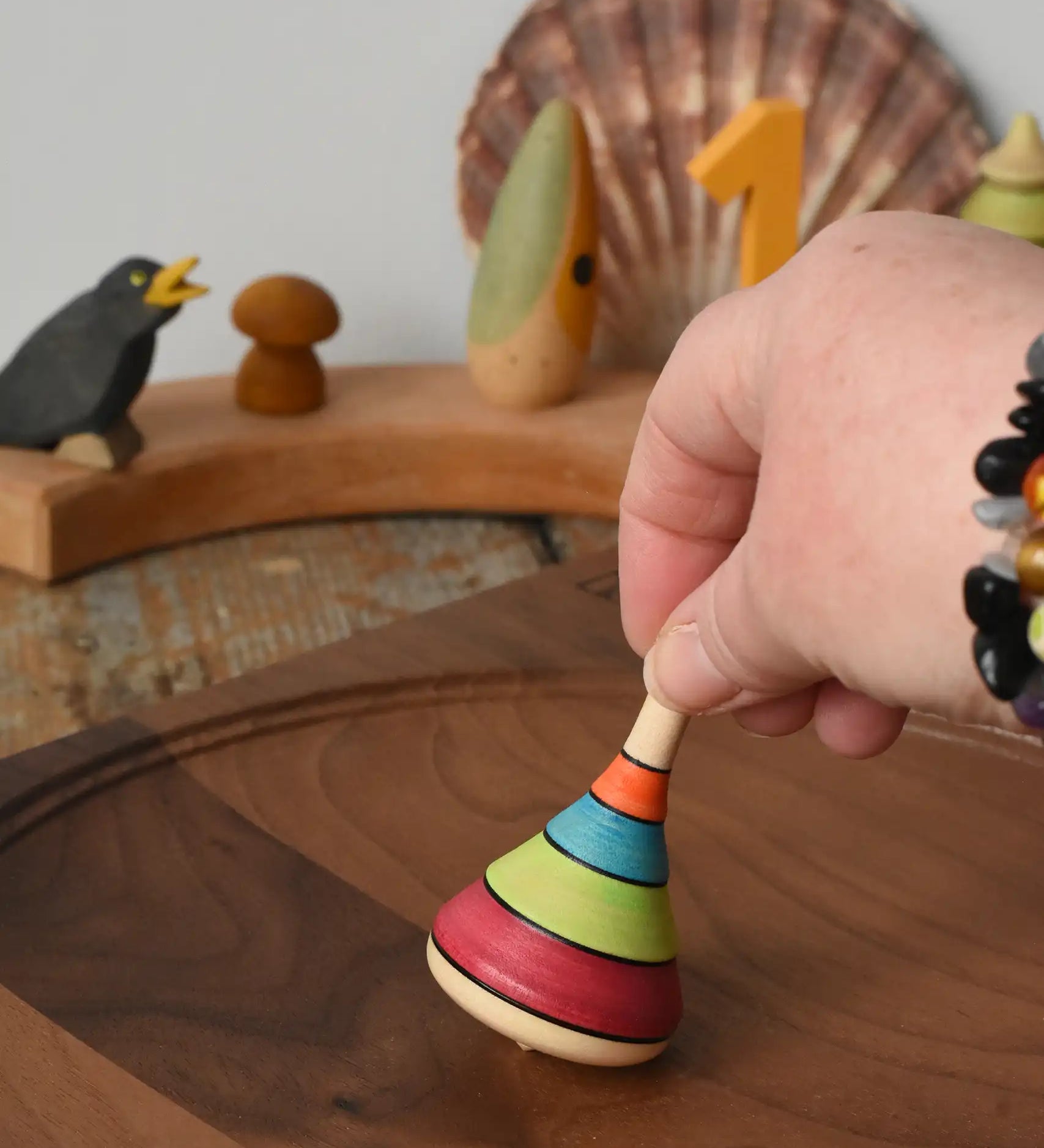 Mader harlekin spinning top being placed on a walnit spinning plate in the Babipur playroom.
