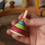 Mader harlekin spinning topin an adult's hand in the Babipur playroom.