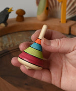 Mader harlekin spinning topin an adult's hand in the Babipur playroom.