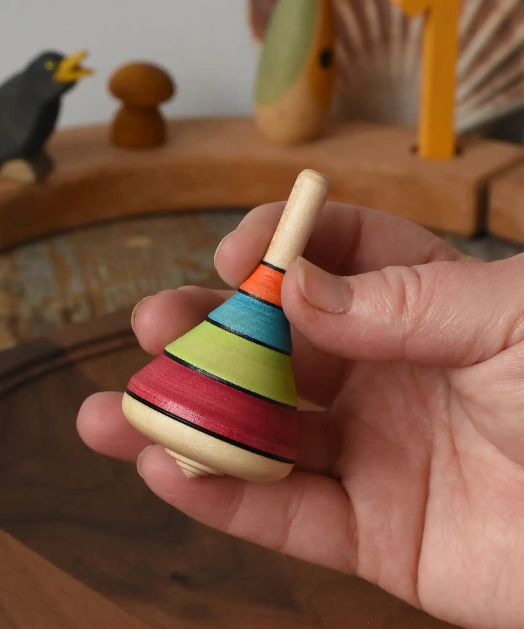 Mader harlekin spinning topin an adult's hand in the Babipur playroom.