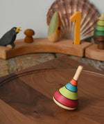 Mader harlekin spinning top placed on a walnut wood spinning plate in the Babipur playroom.