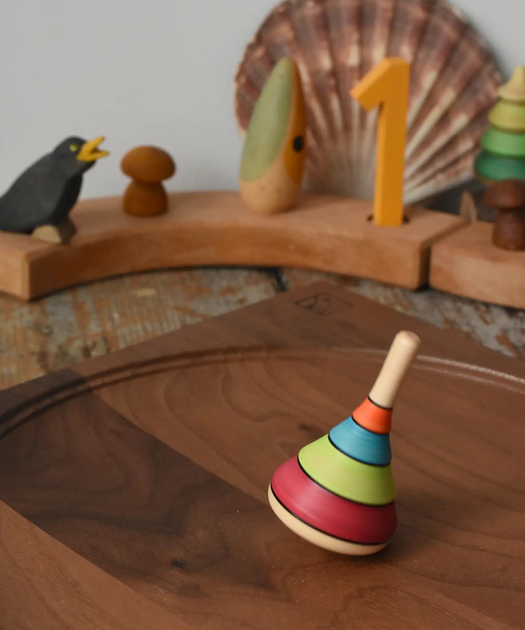 Mader harlekin spinning top placed on a walnut wood spinning plate in the Babipur playroom.