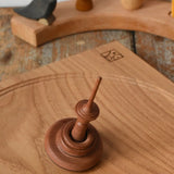 Mader Helene's Captive Rings Apple Spinning Top placed on an oak spinning plate in the Babipur playroom.