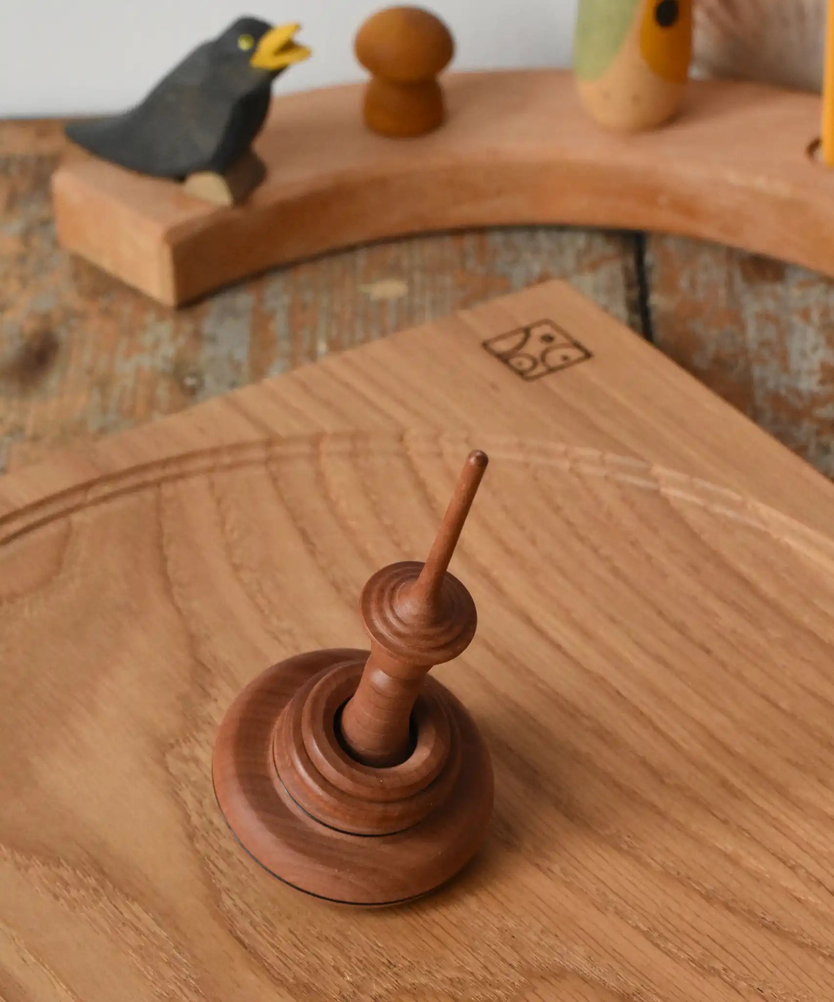 Mader Helene's Captive Rings Apple Spinning Top placed on an oak spinning plate in the Babipur playroom.